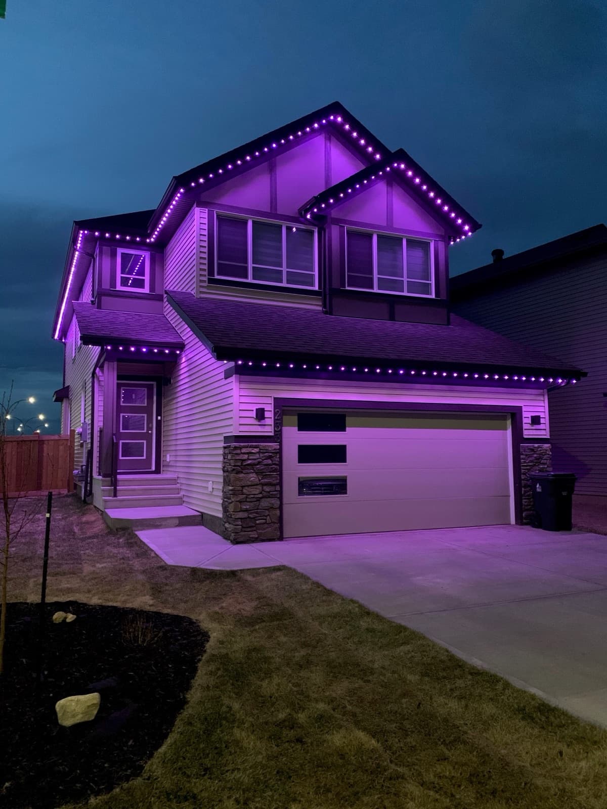 Watts permanent lighting glowing purple on a two-storey home at dusk